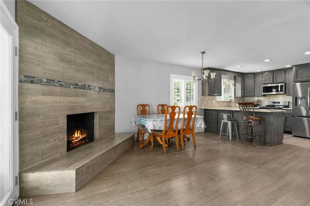 5979 Stanton Ave, Highland, CA 92346 - dining space featuring a chandelier, light wood-style floors, a large fireplace, and recessed lighting
