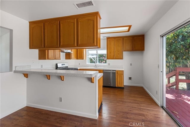 14259 Emelita St, Van Nuys, CA 91401 - kitchen featuring stainless steel appliances, a peninsula, light countertops, dark wood-style flooring, and a kitchen bar