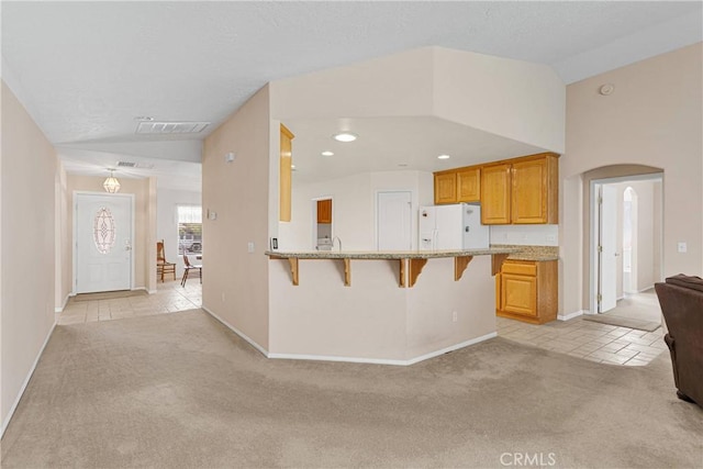 14303 Schooner Dr, Helendale, CA 92342 - kitchen featuring vaulted ceiling, light colored carpet, a breakfast bar area, arched walkways, and baseboards