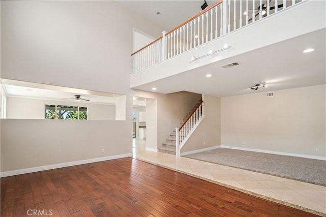 2207 Cork Oak St, Palmdale, CA 93551 - unfurnished living room featuring stairs, wood finished floors, ceiling fan, baseboards, and a towering ceiling