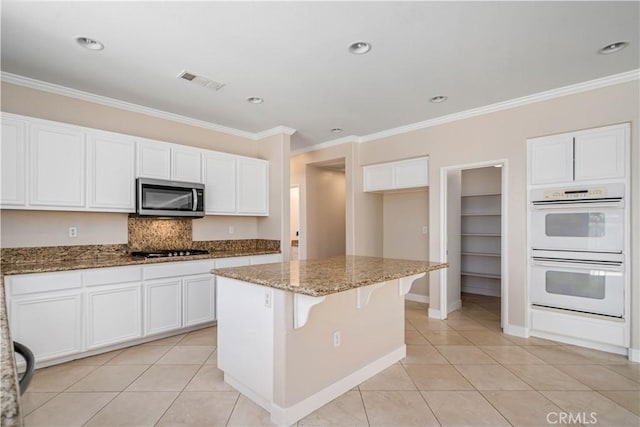 2207 Cork Oak St, Palmdale, CA 93551 - kitchen featuring stainless steel microwave, double oven, light tile patterned floors, stone counters, and ornamental molding
