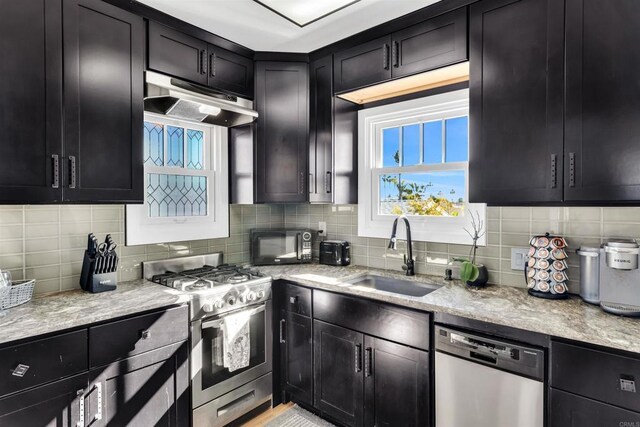 3388 Bancroft St, San Diego, CA 92104 - kitchen featuring appliances with stainless steel finishes, a sink, under cabinet range hood, and dark cabinets