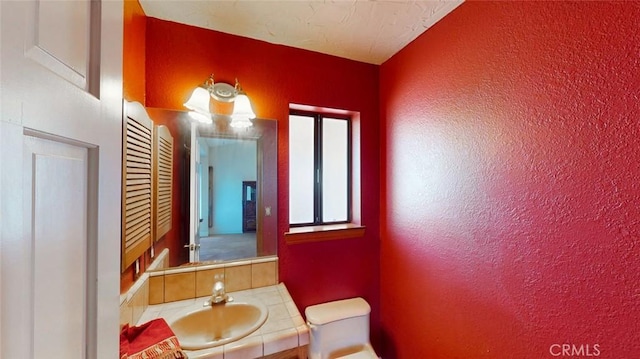 13889 Olathe Rd, Apple Valley, CA 92307 - bathroom featuring toilet, vanity, a textured wall, and tasteful backsplash