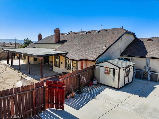 13889 Olathe Rd, Apple Valley, CA 92307 - back of house featuring a patio area, a fenced backyard, central AC unit, and a shingled roof