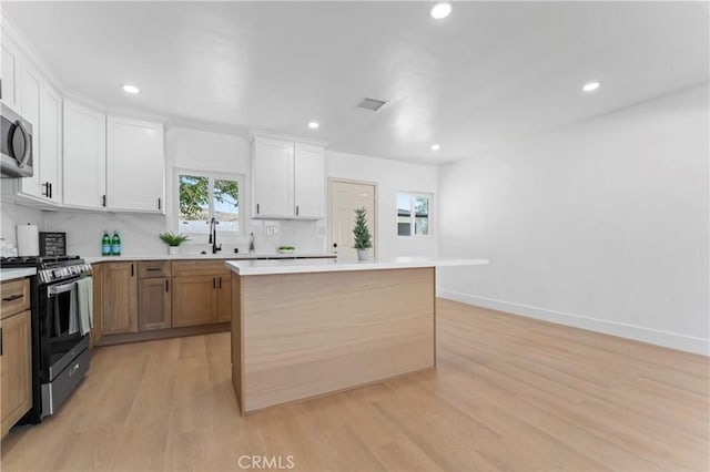 61730 Oleander Dr, Joshua Tree, CA 92252 - kitchen featuring stainless steel appliances, light wood finished floors, a kitchen island, white cabinetry, and recessed lighting