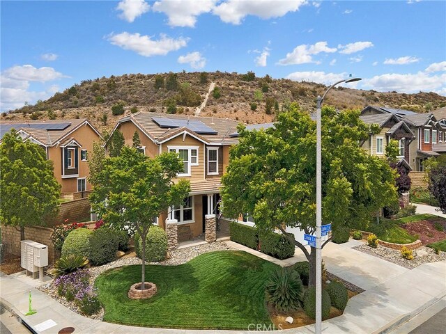 20361 Julia Ln, Saugus, CA 91350 - view of front facade with solar panels, stone siding, a mountain view, a front lawn, and stucco siding