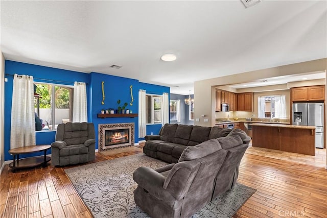 35616 Suzette Ct, Winchester, CA 92596 - living room featuring a chandelier, light wood-type flooring, a glass covered fireplace, and baseboards