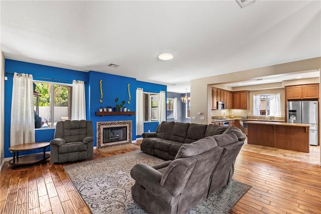 35616 Suzette Ct, Winchester, CA 92596 - living room featuring a chandelier, light wood finished floors, a glass covered fireplace, and baseboards
