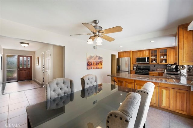 21848 Ute Way, Lake Forest, CA 92630 - kitchen with stainless steel appliances, brown cabinetry, light tile patterned flooring, glass insert cabinets, and decorative backsplash