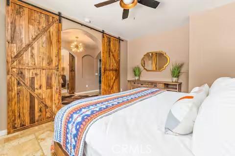 62398 Cope Ln, Joshua Tree, CA 92252 - bedroom featuring a barn door, arched walkways, and a ceiling fan