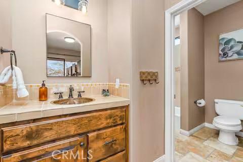 62398 Cope Ln, Joshua Tree, CA 92252 - bathroom with toilet, vanity, backsplash, and baseboards