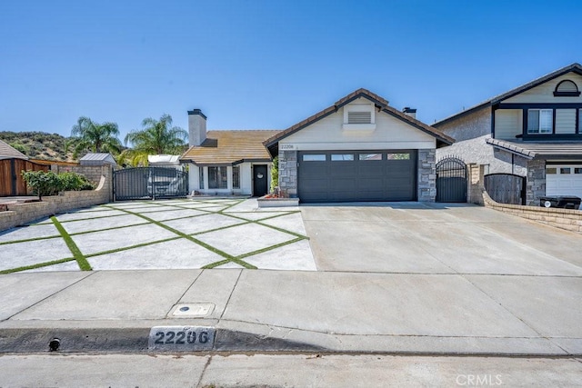22206 Claibourne Ln, Saugus, CA 91350 - single story home featuring a gate, an attached garage, concrete driveway, a chimney, and stone siding