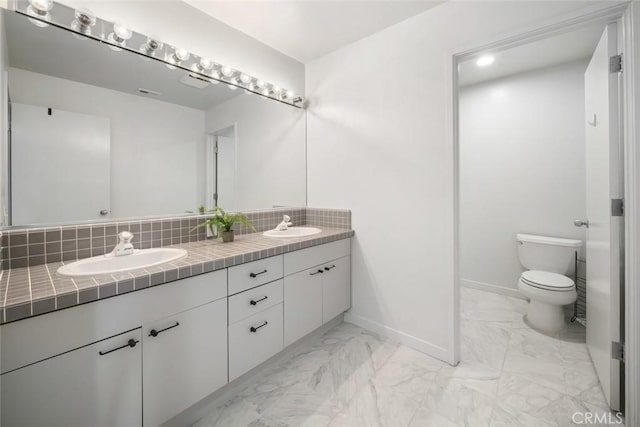 667 Hill St, San Luis Obispo, CA 93405 - bathroom featuring marble look tiles, double vanity, toilet, baseboards, and decorative backsplash