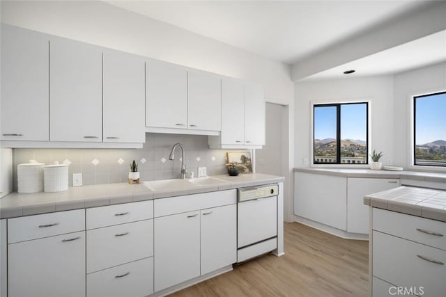 667 Hill St, San Luis Obispo, CA 93405 - kitchen featuring a sink, white dishwasher, light wood-type flooring, decorative backsplash, and white cabinetry