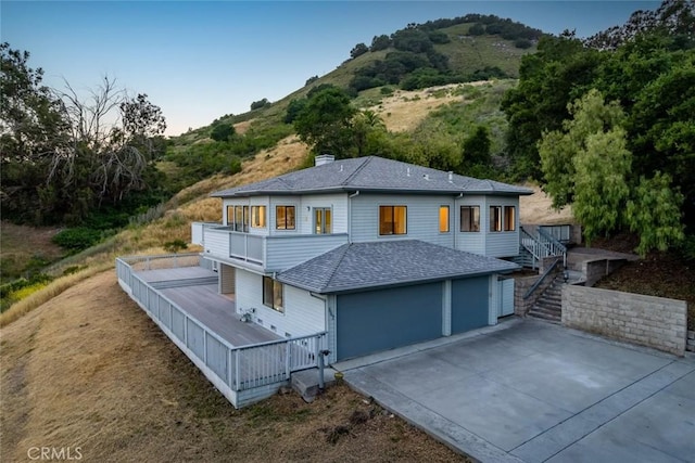 667 Hill St, San Luis Obispo, CA 93405 - rear view of house with a balcony, driveway, an attached garage, a shingled roof, and a chimney