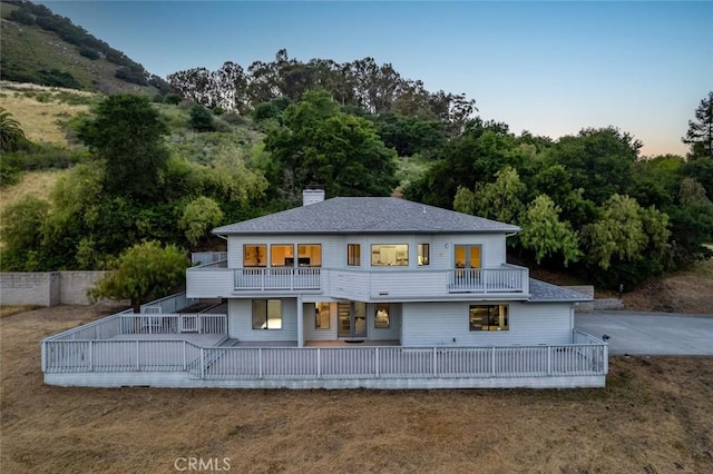 667 Hill St, San Luis Obispo, CA 93405 - back of property at dusk featuring a balcony, a chimney, roof with shingles, and a lawn