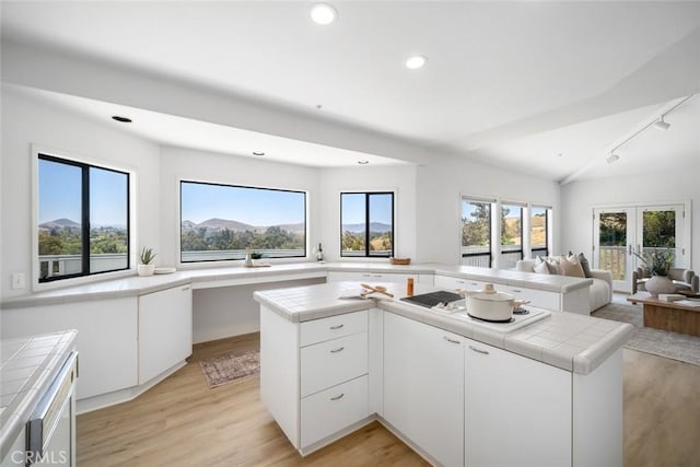 667 Hill St, San Luis Obispo, CA 93405 - kitchen featuring tile countertops, rail lighting, open floor plan, light wood-style flooring, and white cabinets
