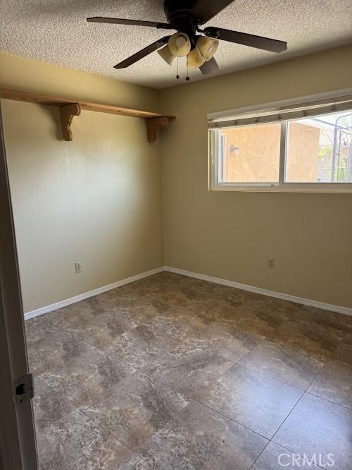 1447 W Westward Ave, Banning, CA 92220 - empty room with plenty of natural light, a ceiling fan, a textured ceiling, and baseboards