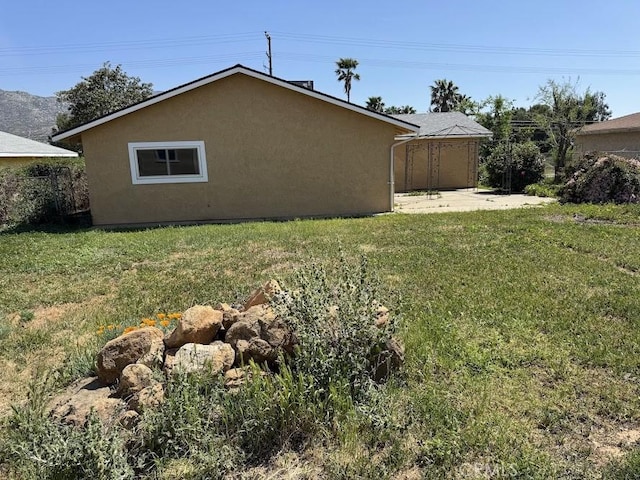 1447 W Westward Ave, Banning, CA 92220 - view of side of property with a yard, stucco siding, and a patio area