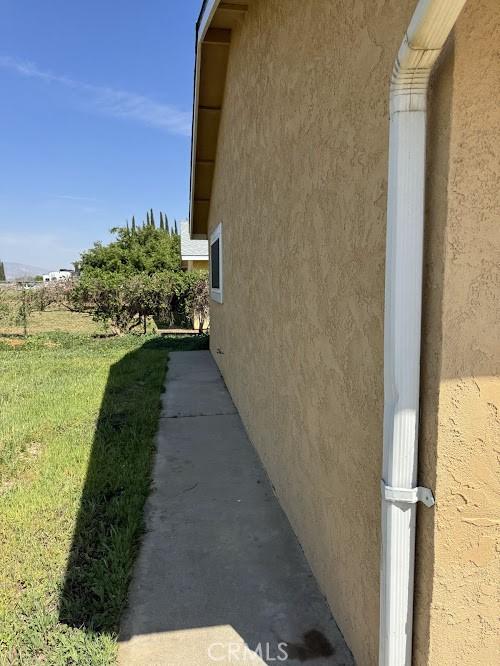 1447 W Westward Ave, Banning, CA 92220 - view of property exterior featuring stucco siding and a yard