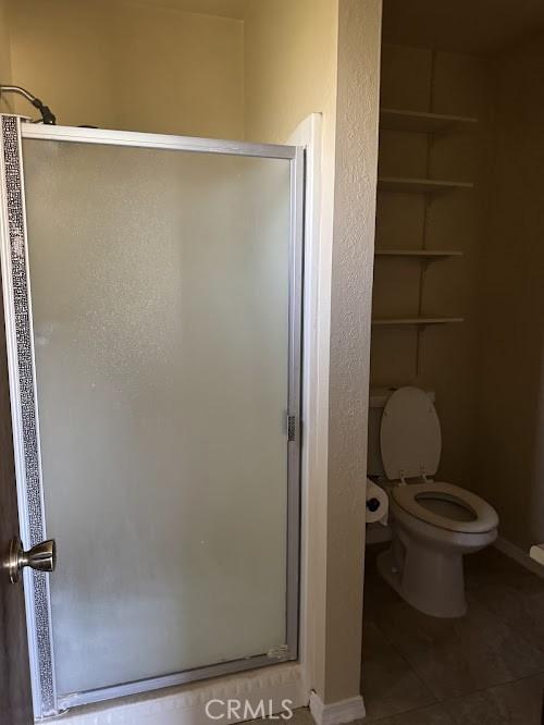 1447 W Westward Ave, Banning, CA 92220 - bathroom featuring a shower stall, toilet, and tile patterned floors