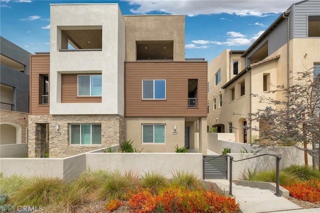 119 Zawn, Irvine, CA 92618 - view of front facade featuring stucco siding, a fenced front yard, stone siding, and a gate