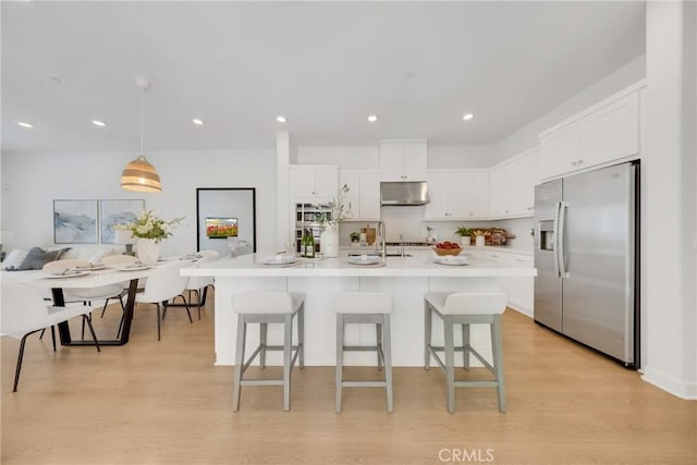119 Zawn, Irvine, CA 92618 - kitchen featuring stainless steel refrigerator with ice dispenser, under cabinet range hood, white cabinets, a kitchen breakfast bar, and recessed lighting