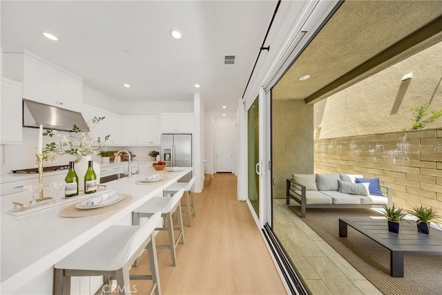 119 Zawn, Irvine, CA 92618 - kitchen featuring stainless steel fridge, under cabinet range hood, light wood finished floors, a sink, and white cabinetry