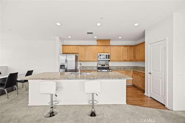 2333 S Via Esplanade Unit 25, Ontario, CA 91762 - kitchen with stainless steel appliances, a sink, a kitchen island with sink, light colored carpet, and light stone countertops