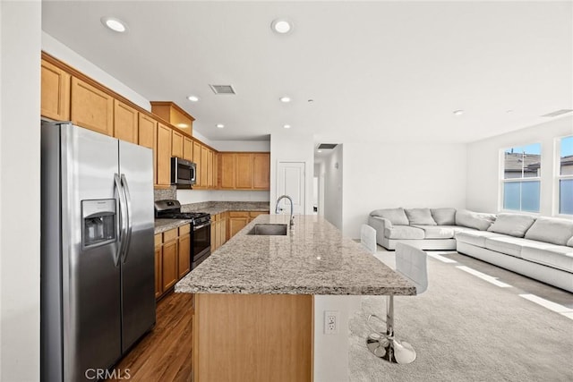 2333 S Via Esplanade Unit 25, Ontario, CA 91762 - kitchen with appliances with stainless steel finishes, a sink, open floor plan, an island with sink, and light stone countertops