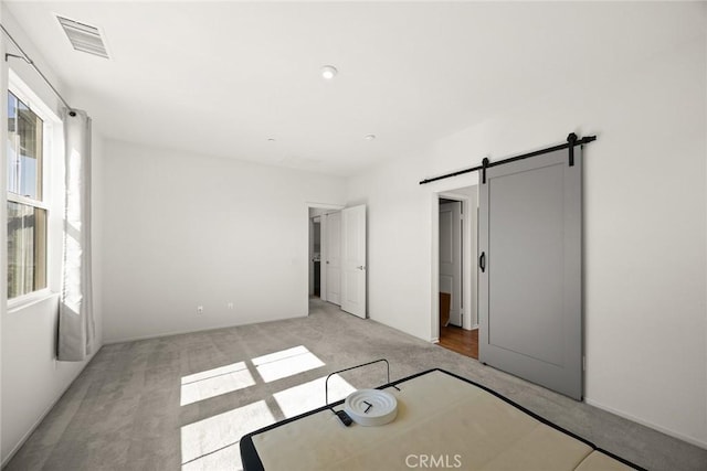 2333 S Via Esplanade Unit 25, Ontario, CA 91762 - unfurnished bedroom with a barn door and light colored carpet