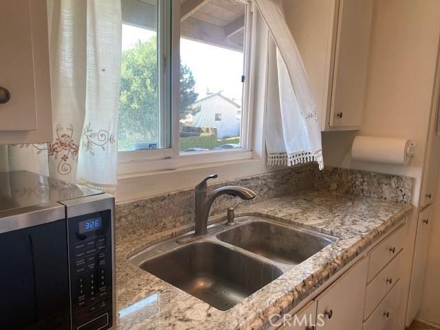7100 Cerritos Ave Unit 112, Stanton, CA 90680 - kitchen featuring stainless steel microwave, a sink, white cabinets, and light stone counters