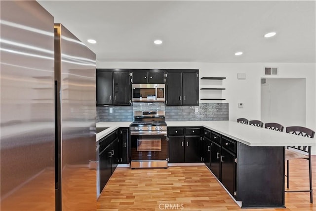 6172 Dalecrest Ave, Woodland Hills, CA 91367 - kitchen with appliances with stainless steel finishes, dark cabinets, a breakfast bar area, light countertops, and open shelves