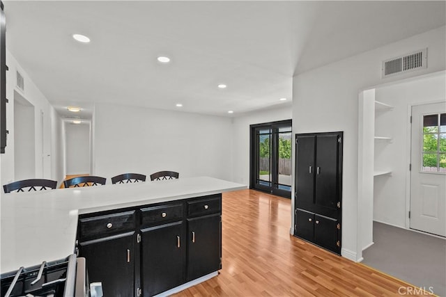6172 Dalecrest Ave, Woodland Hills, CA 91367 - kitchen with dark cabinetry, light countertops, recessed lighting, light wood-type flooring, and a kitchen bar