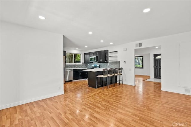 6172 Dalecrest Ave, Woodland Hills, CA 91367 - kitchen featuring stainless steel appliances, dark cabinets, light countertops, a breakfast bar, and light wood-type flooring