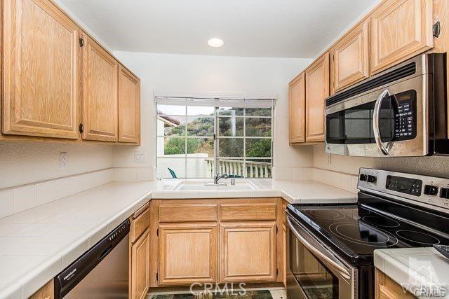 5805 Oak Bend Ln Unit 407, Oak Park, CA 91377 - kitchen featuring appliances with stainless steel finishes, tile counters, a sink, and light brown cabinets