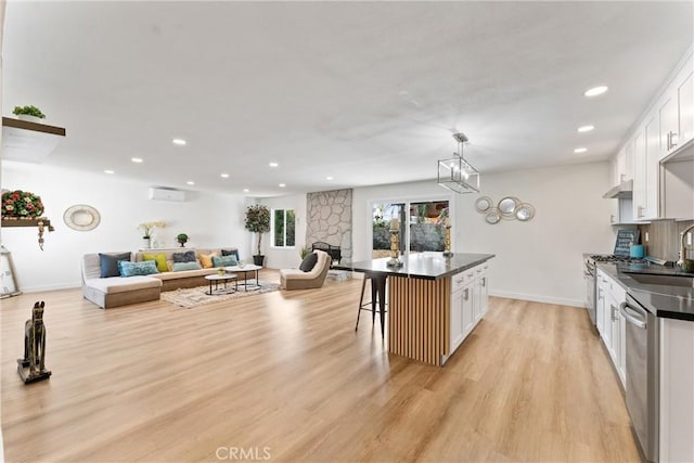 17924 E Kelby St, Covina, CA 91722 - kitchen with dark countertops, a sink, light wood-type flooring, white cabinetry, and a breakfast bar area
