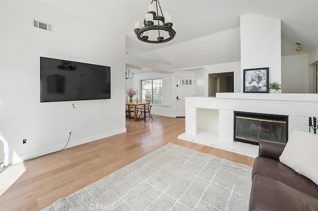 24148 Saint Moritz Dr, Valencia, CA 91355 - living room with wood finished floors, a chandelier, baseboards, vaulted ceiling, and a fireplace