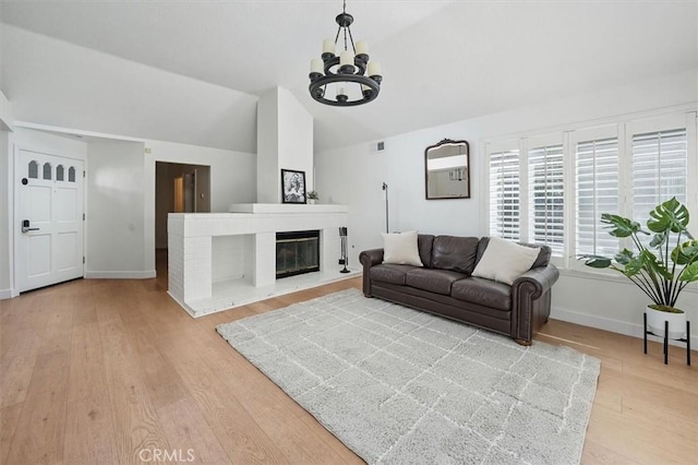 24148 Saint Moritz Dr, Valencia, CA 91355 - living area with light wood-type flooring, vaulted ceiling, baseboards, a chandelier, and a glass covered fireplace