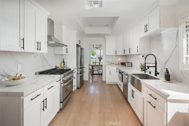 24148 Saint Moritz Dr, Valencia, CA 91355 - kitchen with high quality appliances, wall chimney exhaust hood, a sink, a raised ceiling, and decorative backsplash