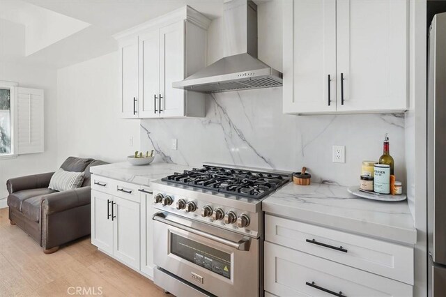 24148 Saint Moritz Dr, Valencia, CA 91355 - kitchen featuring appliances with stainless steel finishes, wall chimney range hood, light stone countertops, light wood-style flooring, and tasteful backsplash