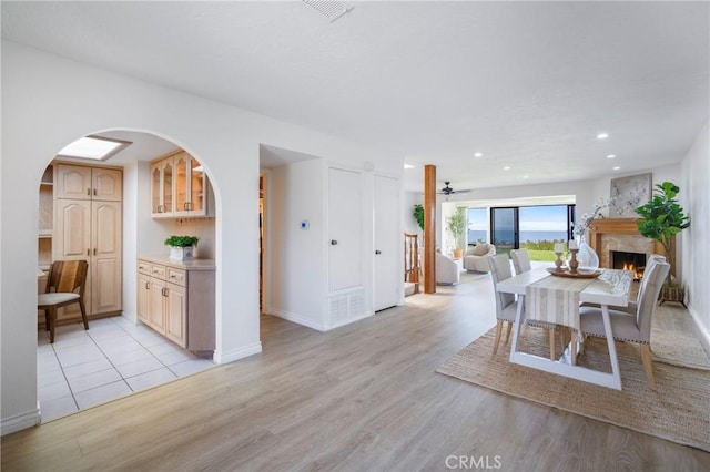 319 Calle Cuervo, San Clemente, CA 92672 - dining area with arched walkways, light wood-style flooring, baseboards, a lit fireplace, and recessed lighting