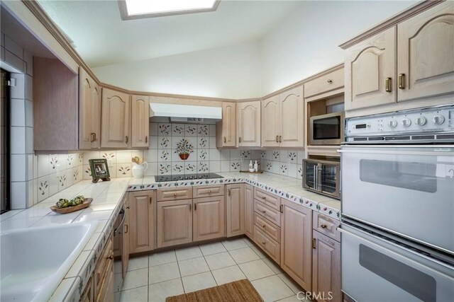 319 Calle Cuervo, San Clemente, CA 92672 - kitchen with appliances with stainless steel finishes, vaulted ceiling, backsplash, under cabinet range hood, and light brown cabinetry