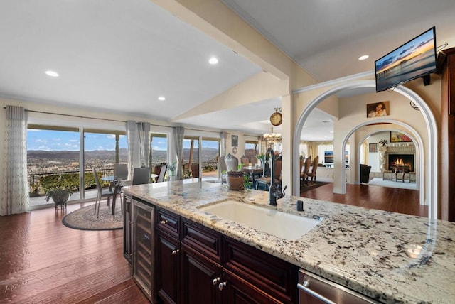 10310 Fuerte Dr, La Mesa, CA 91941 - kitchen with light stone counters, dark wood-type flooring, beverage cooler, recessed lighting, and a warm lit fireplace