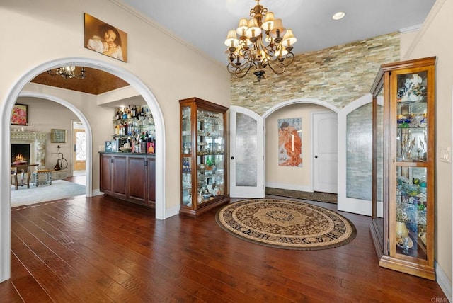 10310 Fuerte Dr, La Mesa, CA 91941 - entrance foyer featuring a chandelier, hardwood / wood-style flooring, arched walkways, ornamental molding, and a warm lit fireplace