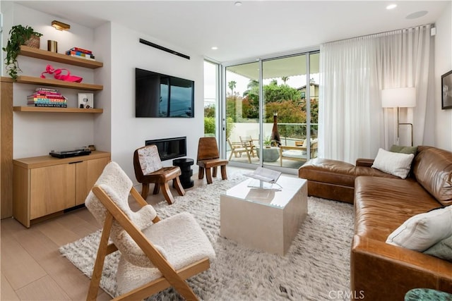 68 E F St, Encinitas, CA 92024 - living room featuring floor to ceiling windows, light wood finished floors, a glass covered fireplace, and recessed lighting