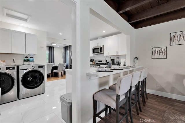 254 Piedmont Ave, Claremont, CA 91711 - kitchen featuring washing machine and clothes dryer, stainless steel appliances, a breakfast bar area, light wood-type flooring, and light countertops