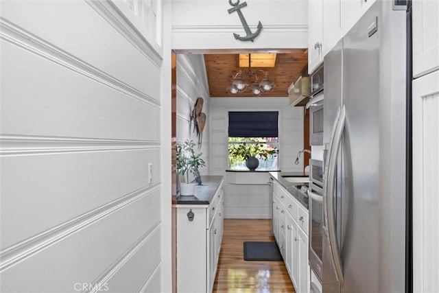 41 19th St, Cayucos, CA 93430 - kitchen with freestanding refrigerator, white cabinetry, wood finished floors, a chandelier, and a sink