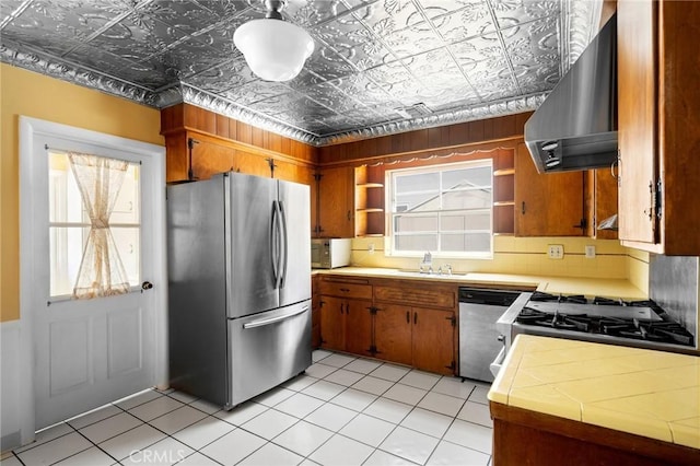 13617 Bassett St, Valley Glen, CA 91405 - kitchen with stainless steel appliances, wall chimney exhaust hood, open shelves, tile counters, and an ornate ceiling