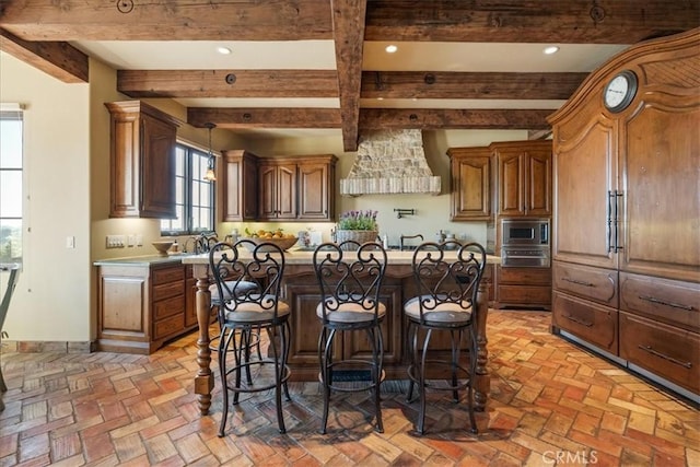 1470 Via Chaparral, Fallbrook, CA 92028 - kitchen featuring stainless steel microwave, beam ceiling, a center island, a kitchen breakfast bar, and light countertops